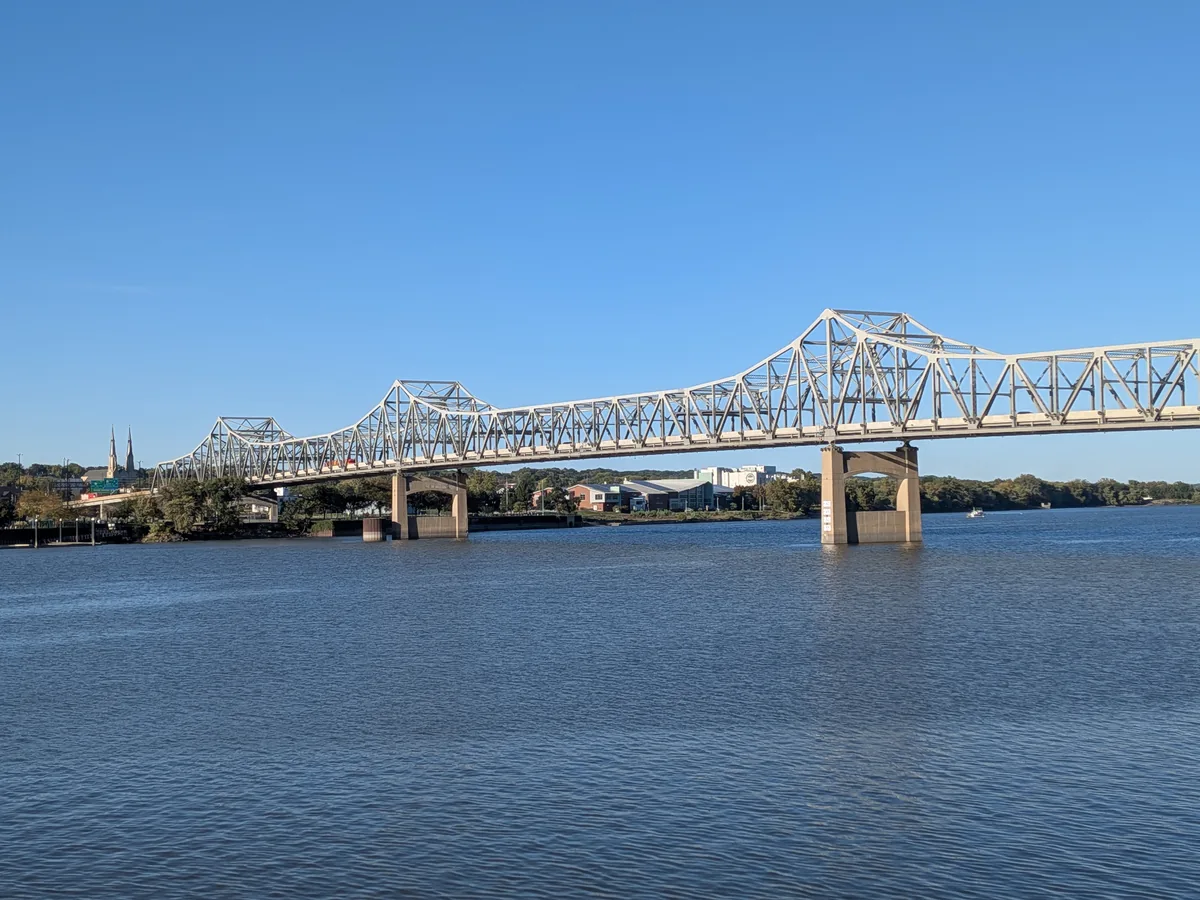 The white steel truss bridge stretching across the river toward the church spires