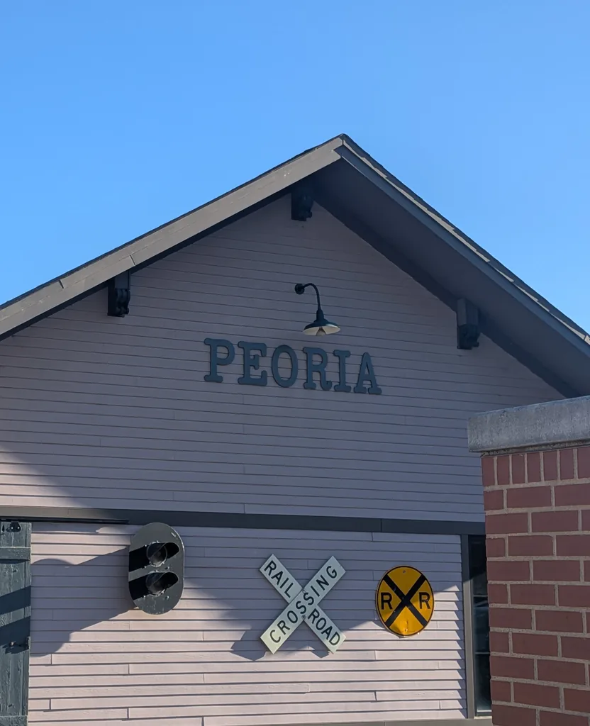 The old Peoria railroad depot with its PEORIA sign and crossing signals
