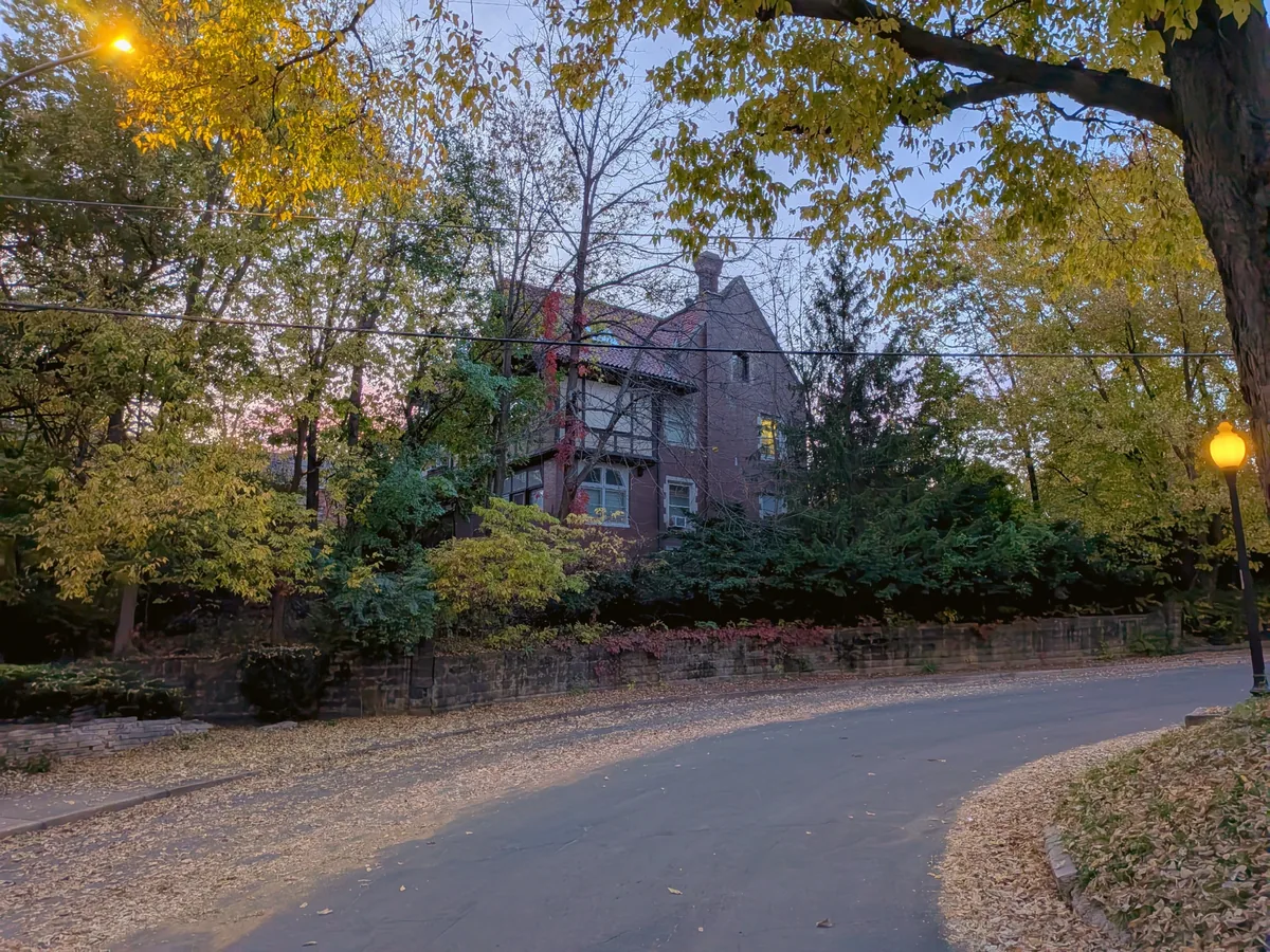 A brick Tudor with half-timbering above an old stone wall at dusk